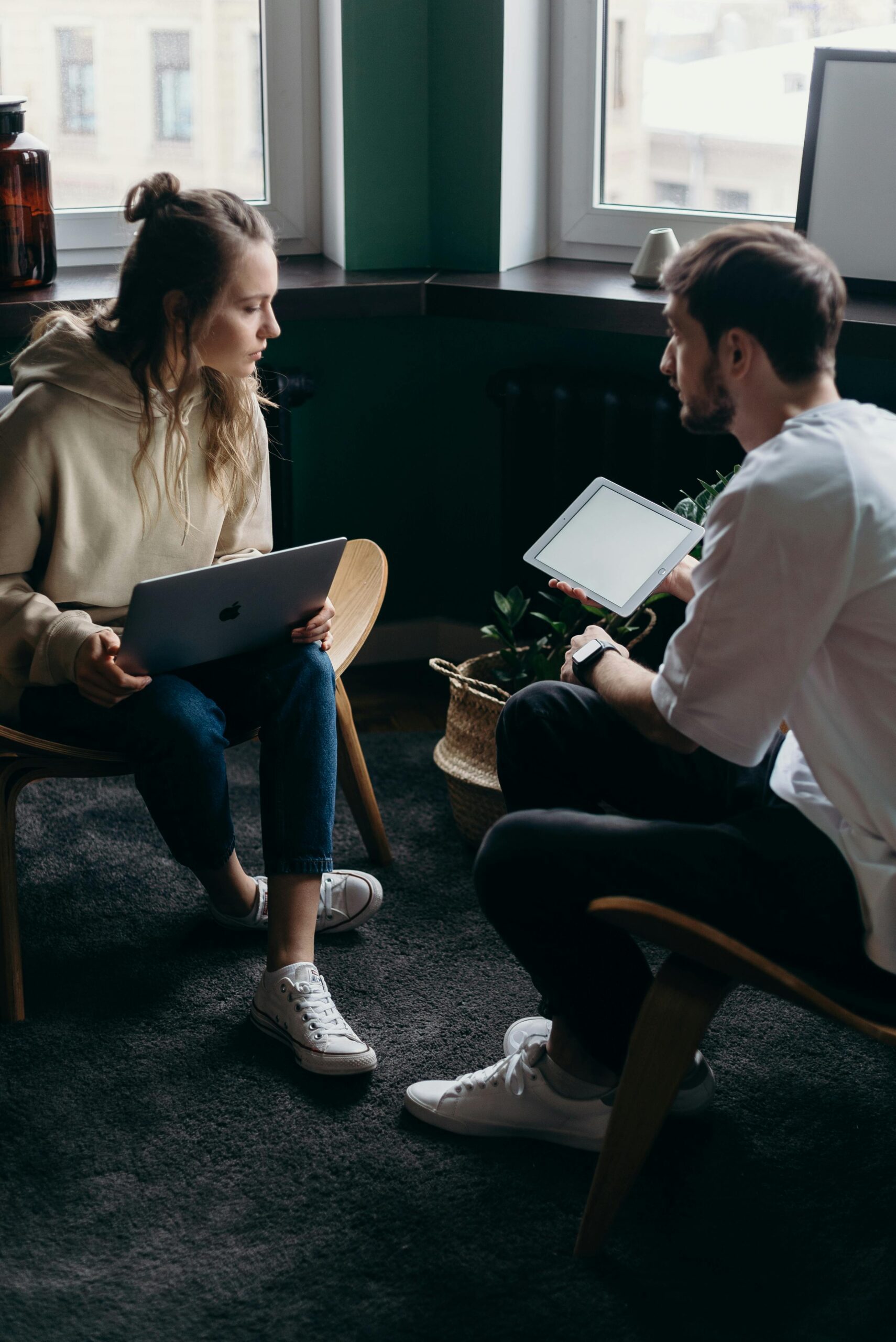 Two adults having a tech-focused discussion in a cozy home setting.